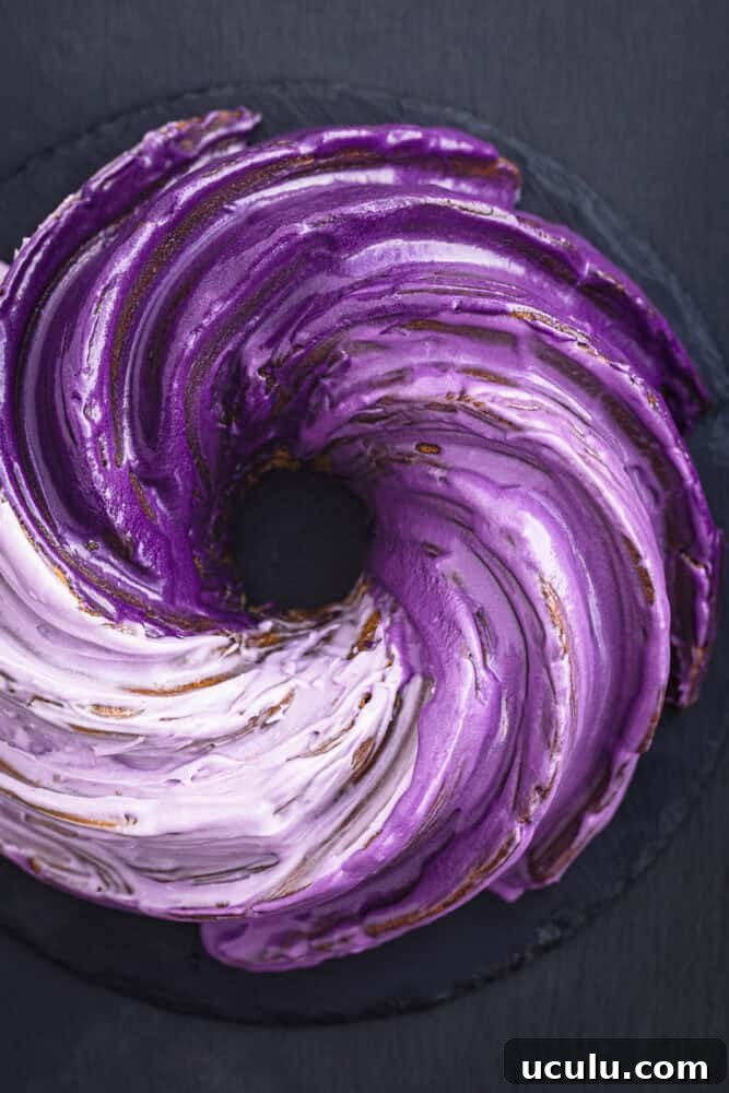 Crème fraîche Bundt cake with dramatic ombré purple ube glaze, overhead shot on dark background