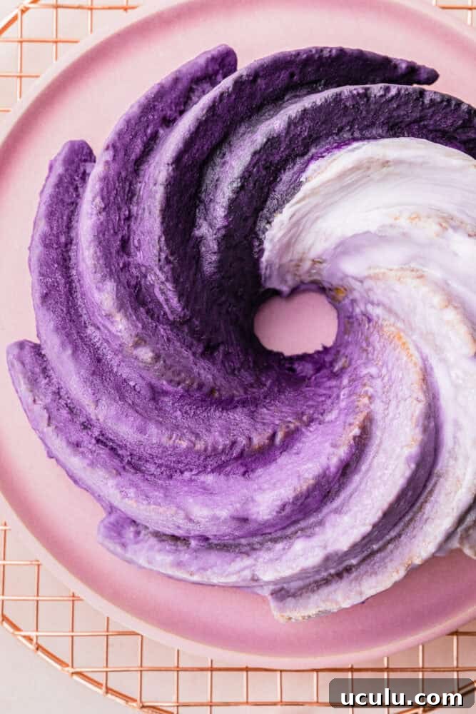 Ube cake with lavender to deep purple ombré glaze on a pink plate, overhead shot