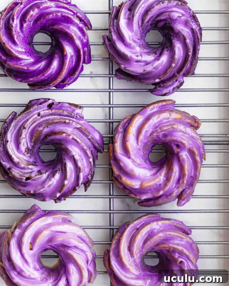 Six mini ube glazed Bundt cakes on a wire rack showing range of purple glaze shades, overhead shot