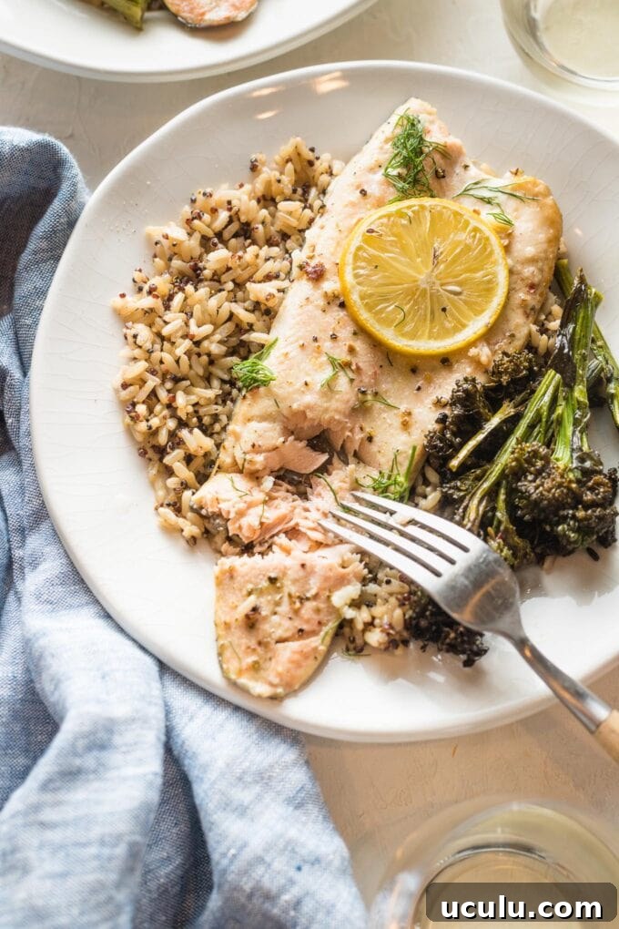 Close up of baked rainbow trout served on a plate, being flaked with a table fork.
