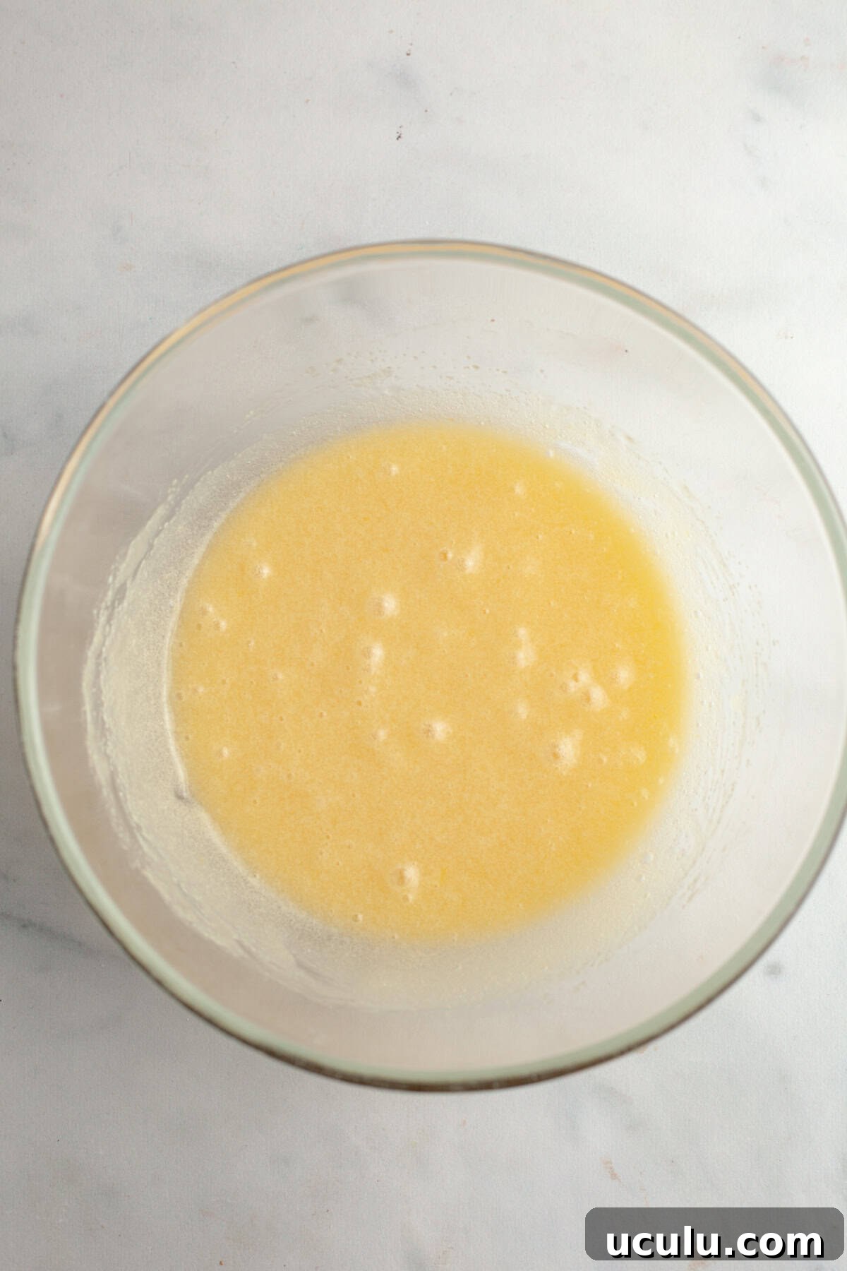 A glass bowl with a beige liquid in it.