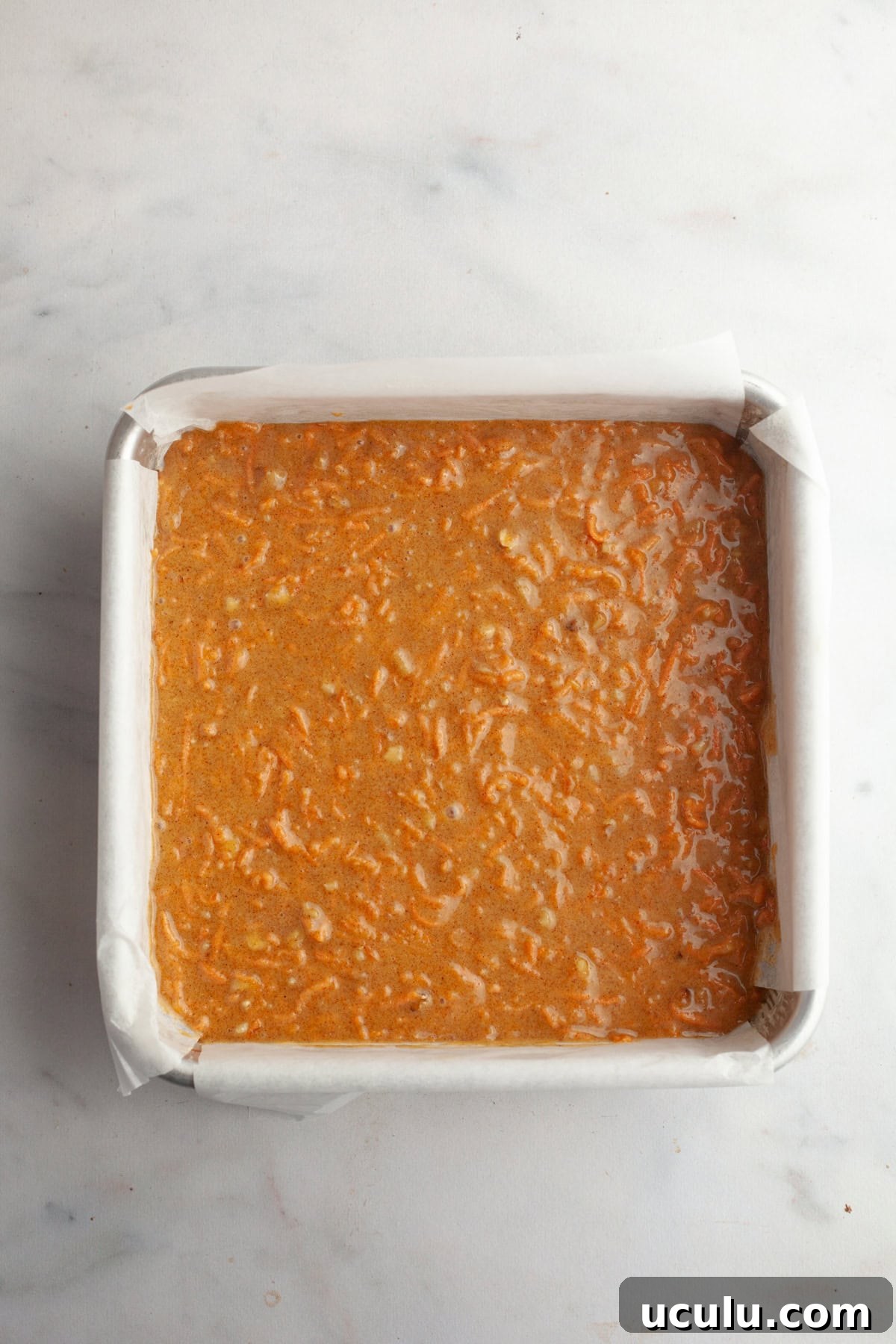 Unbaked carrot cake in a square pan.