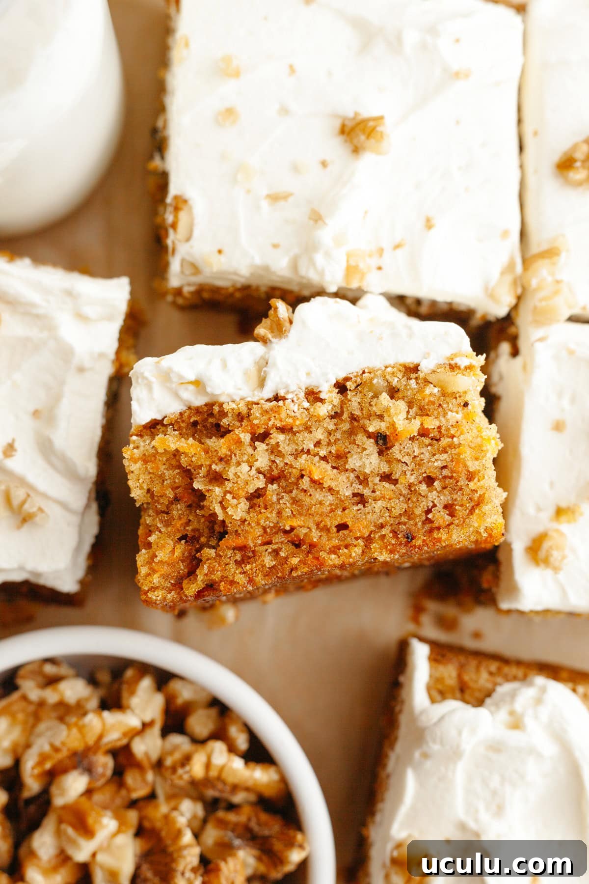 A close up of a square slice of a mini carrot snack cake with cream cheese frosting.