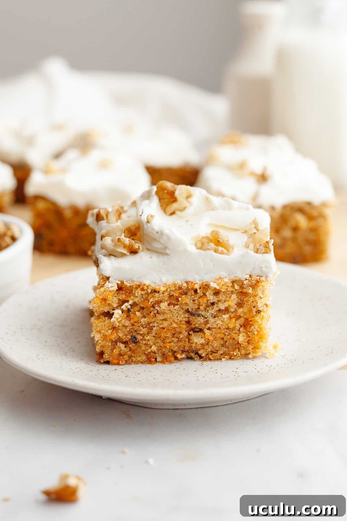 A slice of mini carrot cake with cream cheese frosting on a small plate.