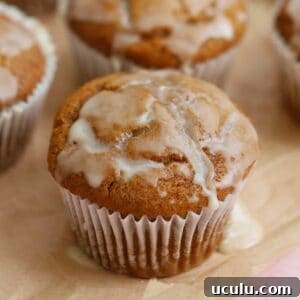 Gluten free pumpkin banana muffins with maple glaze on a sheet of parchment paper.