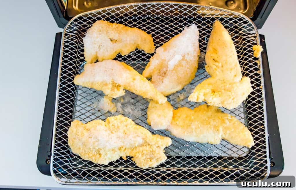 Frozen chicken tenders in an air fryer.