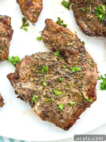 Cooked lamb chops on a plate, garnished with fresh parsley.