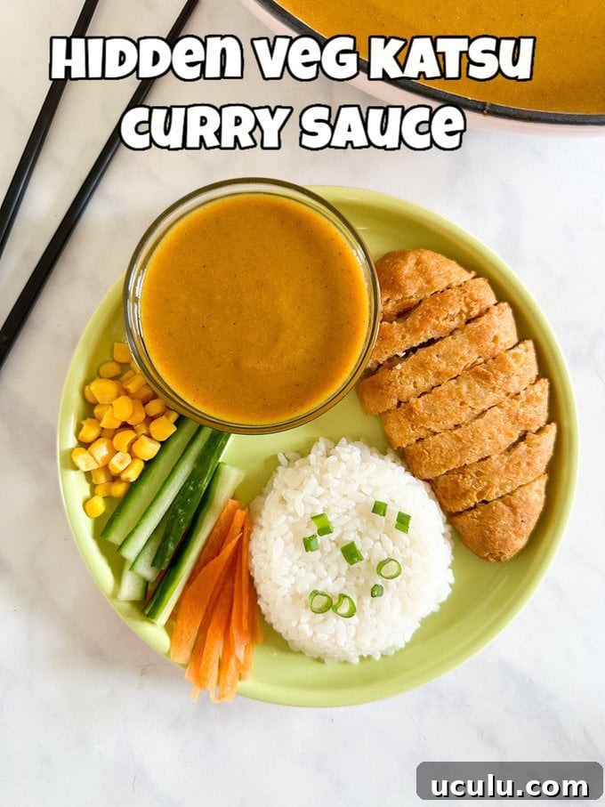 Hidden veg Katsu curry sauce served in a small,round glass dipping bowl alongside a battered chicken breast, white rice and chopping veggies.
