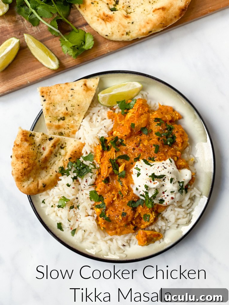 Slow cooker chicken Tikka Masala served with white rice and a small naan bread on the side, garnished with chopped coriander.