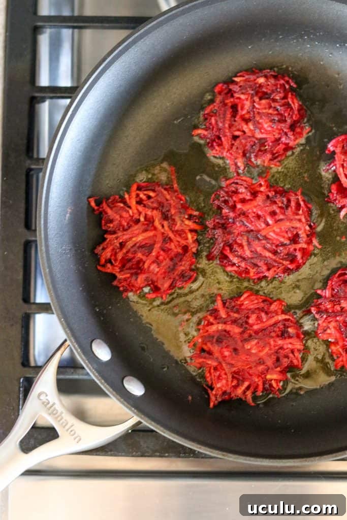 Beet and celery root cakes in a pan cooking on the stove