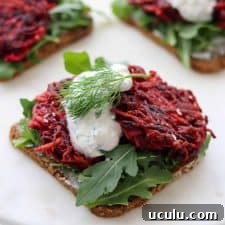An open sandwich with beet and celery root cakes and creamy sauce on a plate