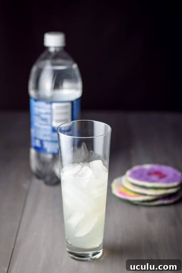 The contents of the shaker poured into the glass with club soda in the background