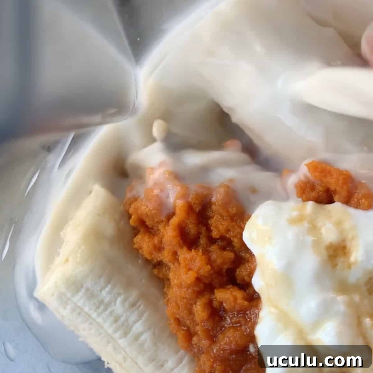 Close-up of a banana, pumpkin puree, and yogurt in a blender as milk is being poured in.