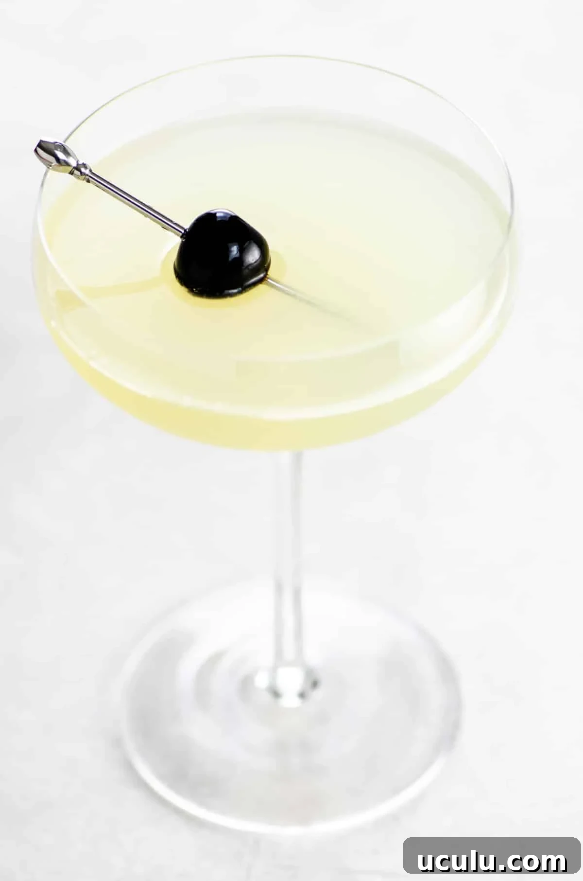 The Last Word cocktail in a coupe glass garnished with a Luxardo cherry on a cocktail skewer