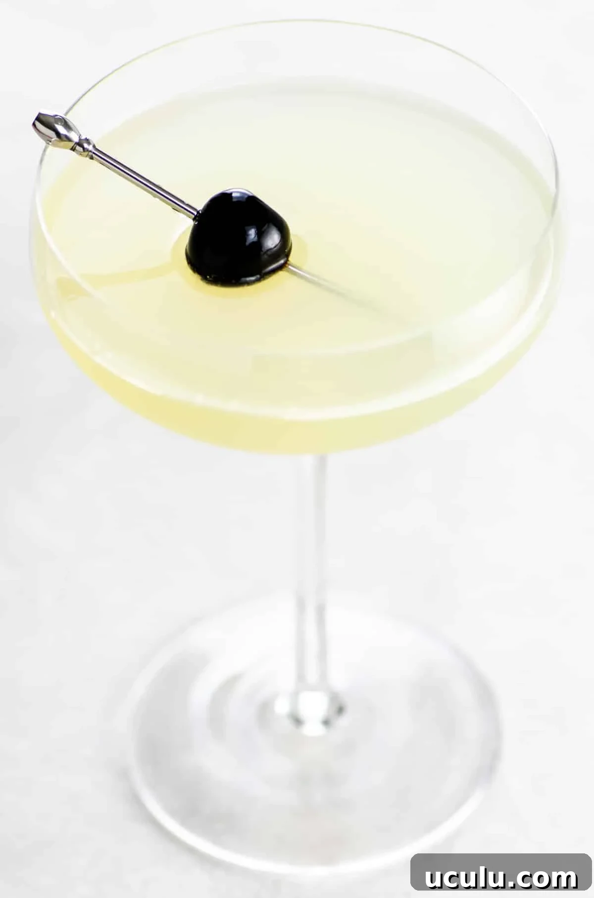The Last Word cocktail in a coupe glass garnished with a Luxardo cherry on a cocktail skewer