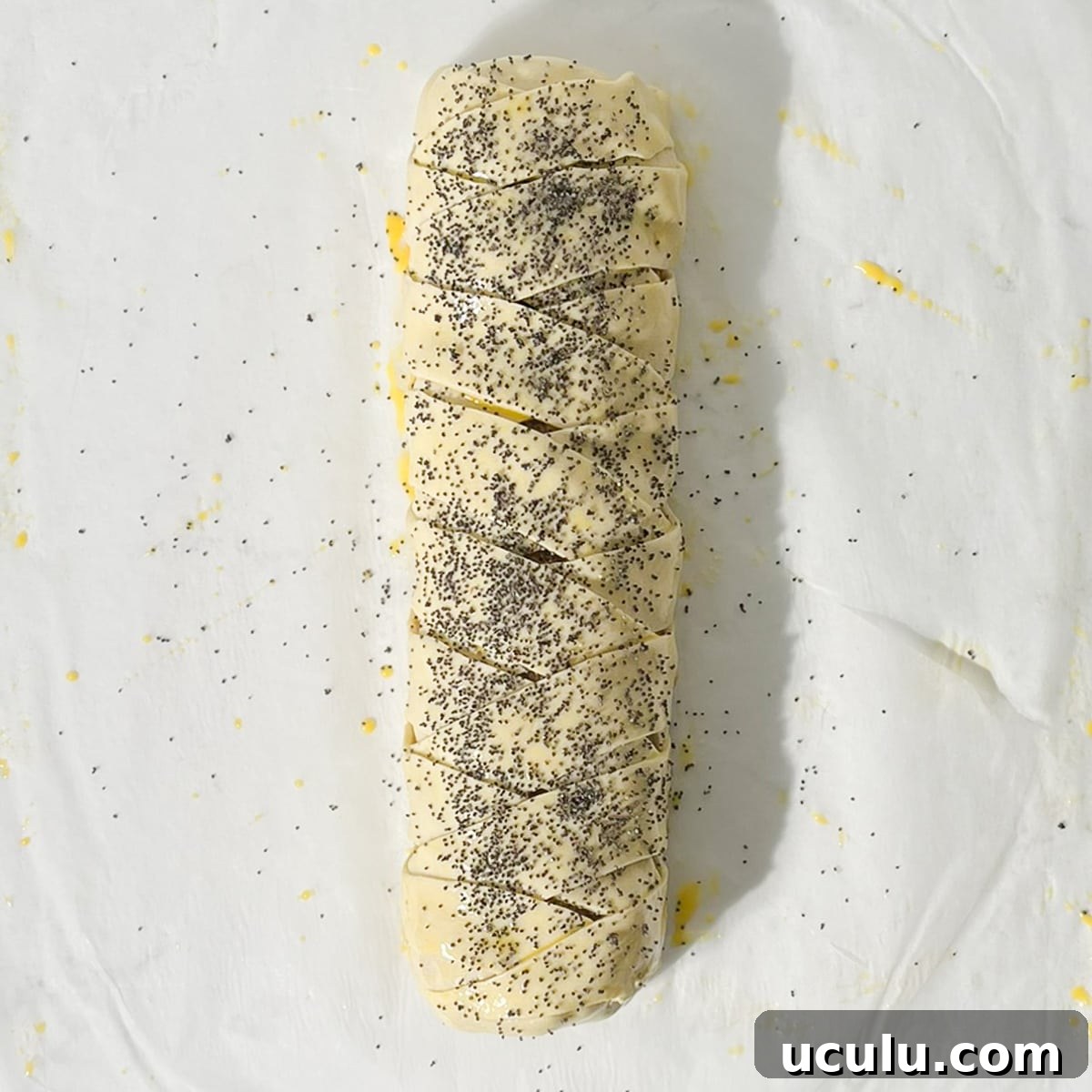Sprinkling poppy seeds onto the giant sausage roll.