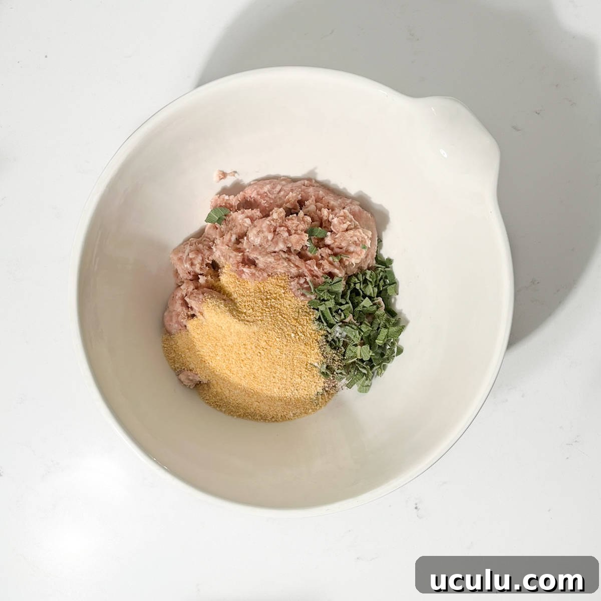 Adding the breadcrumbs, sage and sausage meat to a large bowl.