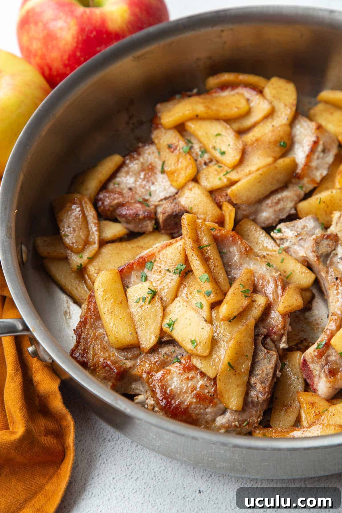 pork chops and apples in a metal skillet.