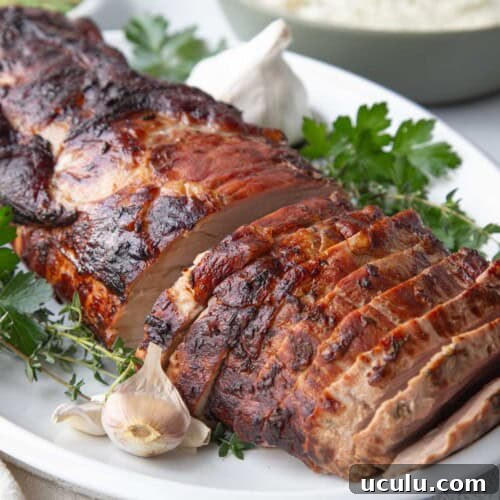 sliced marinated pork loin roast on a white platter.