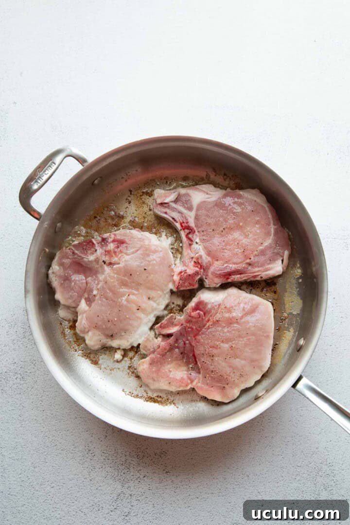 raw pork chops in a skillet.