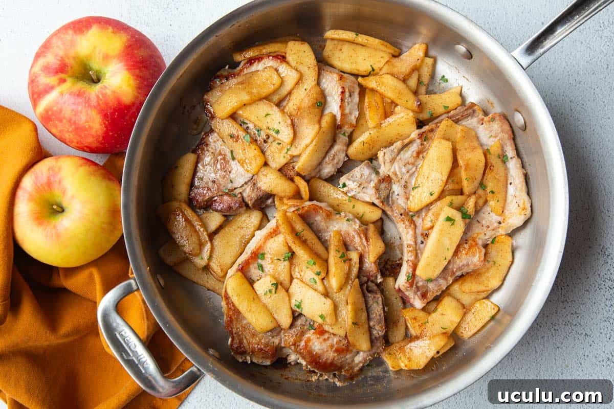 skillet filled with pork chops and apples.