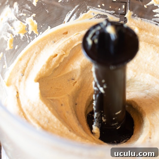 Puréeing hummus in the container of a food processor.