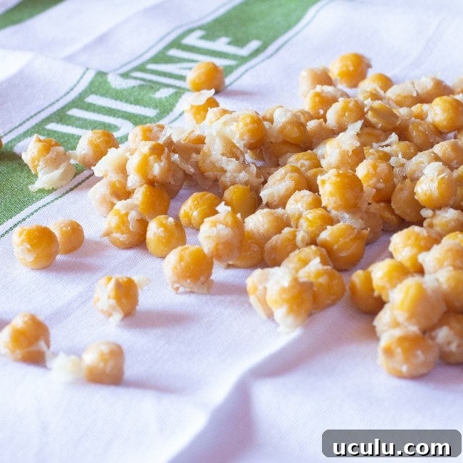 Cooked chickpeas spread on a towel, with skins partly falling off. 