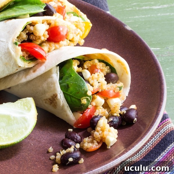 Flour tortilla wraps with quinoa, black beans, tomatoes, spinach leaves and hummus.