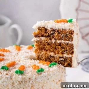 Cake server holding up a slice of 3-layered carrot cake.