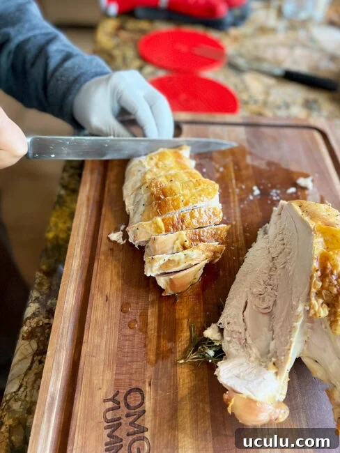 Slicing the first half of the turkey breast that has been removed from the bone.