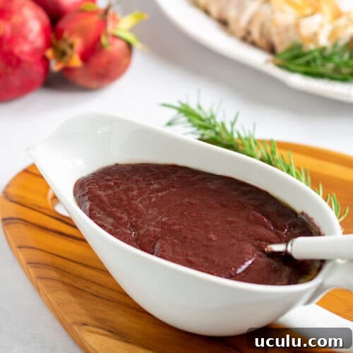 Pomegranate sauce in a gravy boat with a spoon and the sliced turkey breast in the background.