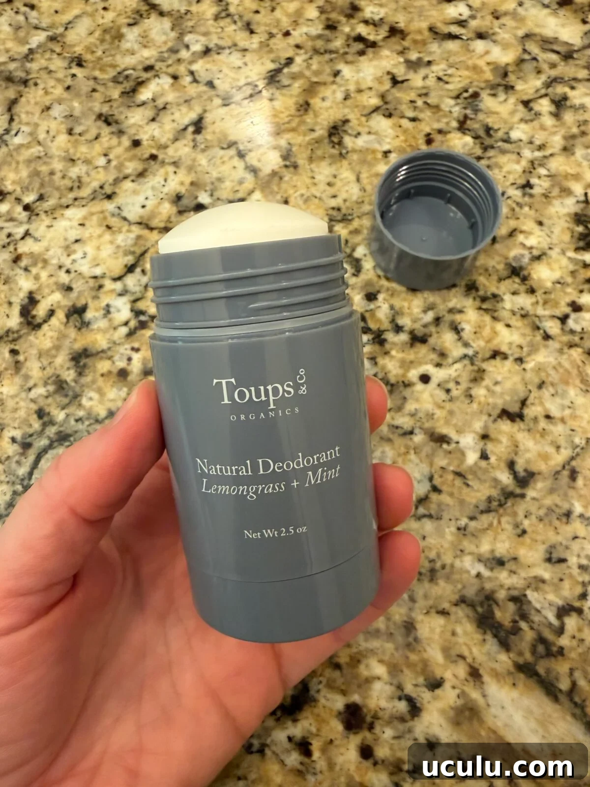 Hand holding Toups & Organics Extra-Strength Natural Deodorant in Lemongrass Mint, 2 oz stick