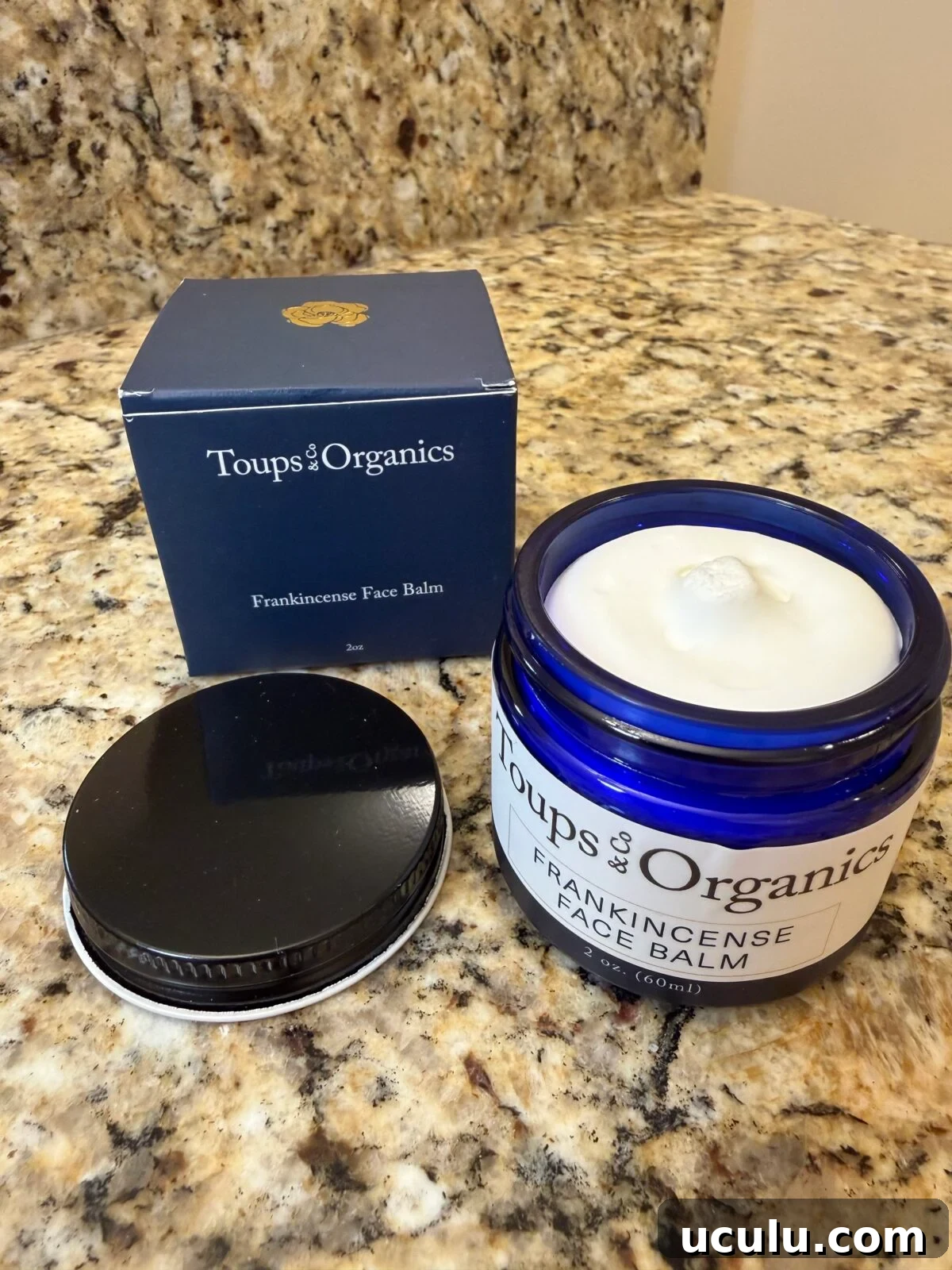 Toups & Organics Frankincense Face Balm in blue glass jar with navy box on granite counter