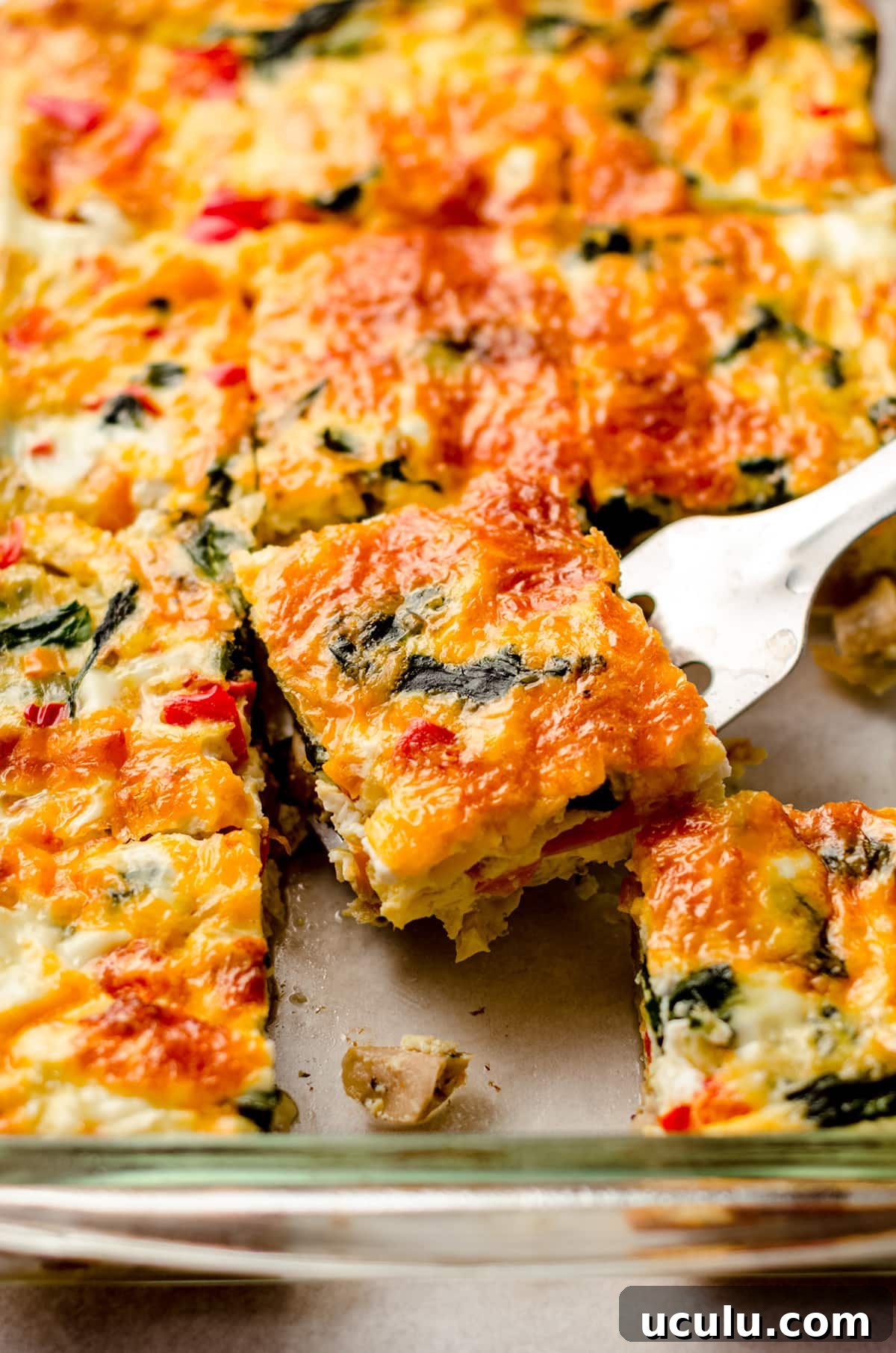 freezer breakfast casserole sliced in a dish and a spatula is taking a slice out to serve it