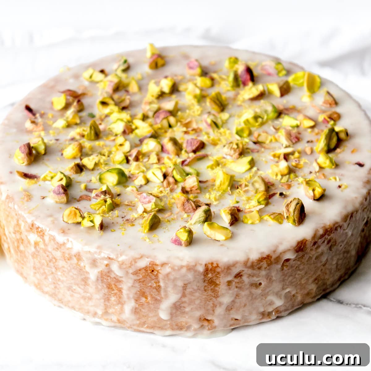 Vegan olive oil cake drizzled with glaze and topped with pistachios