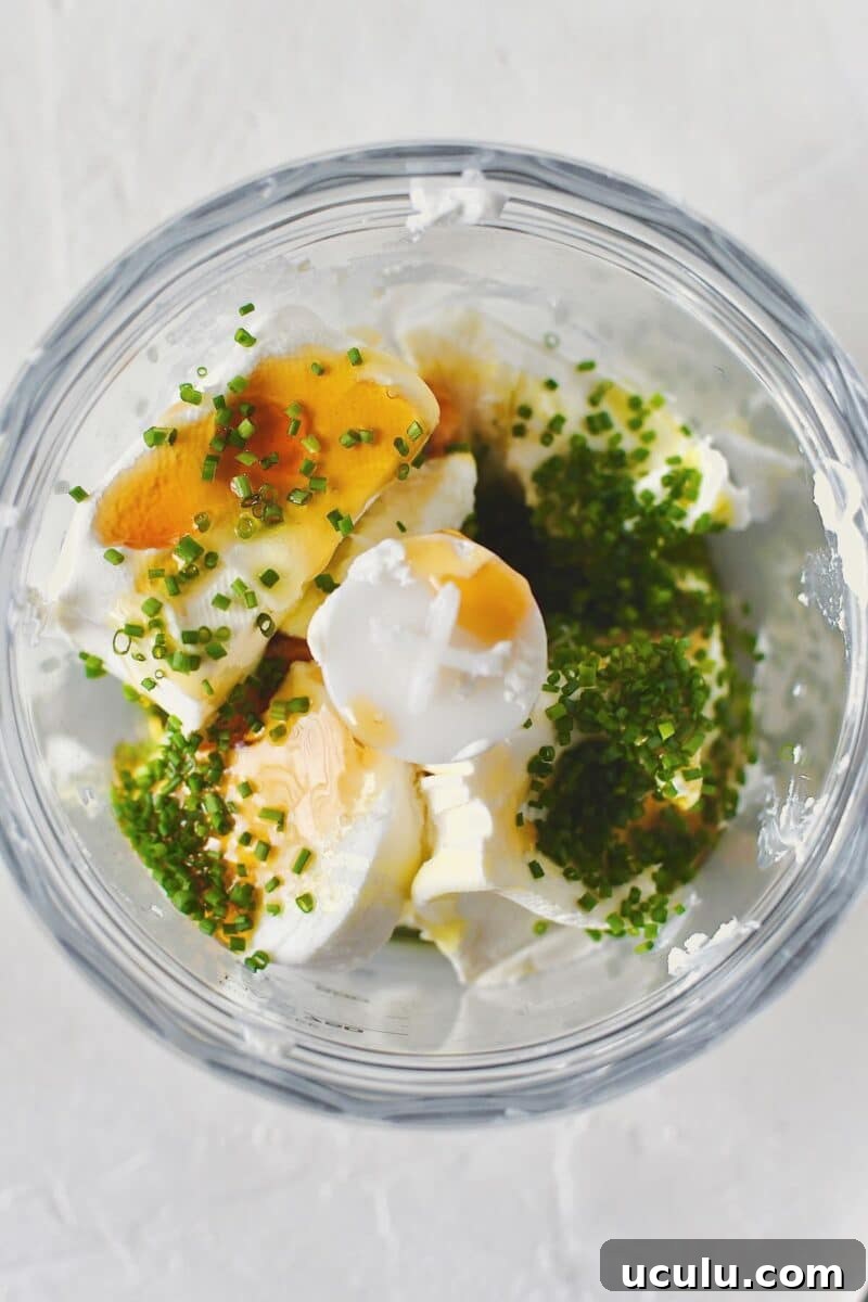 Goat cheese, cream cheese, wildflower honey, olive oil, chives, salt, and pepper, place in a mini food processor ready to be whipped.