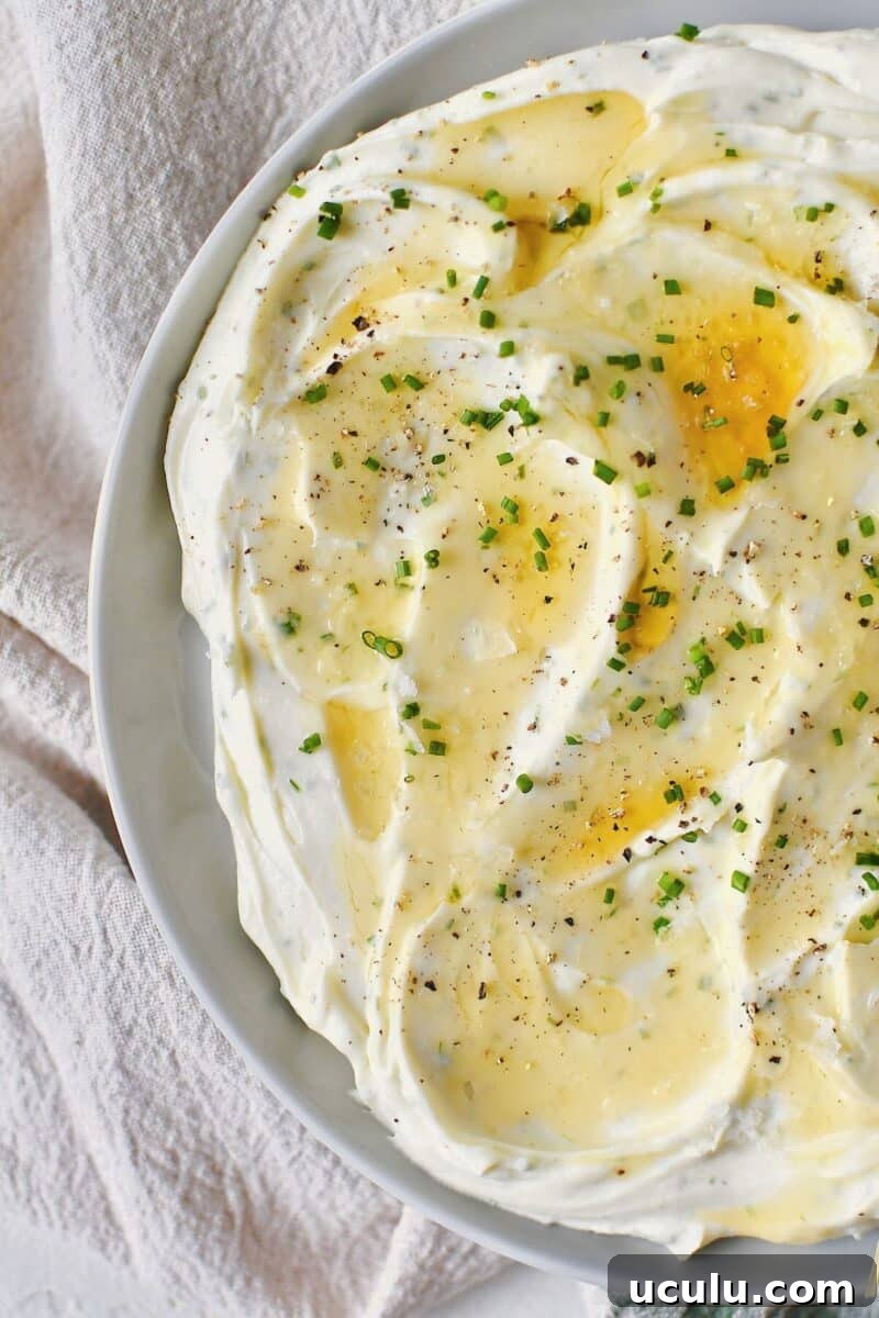 Whipped Goat Cheese spread on a plate and topped with lavender honey, chives, and sea salt.