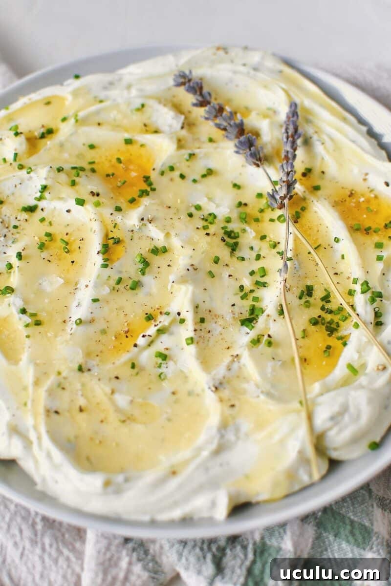 Whipped Goat Cheese spread on a plate and topped with lavender honey, chives, and sea salt.