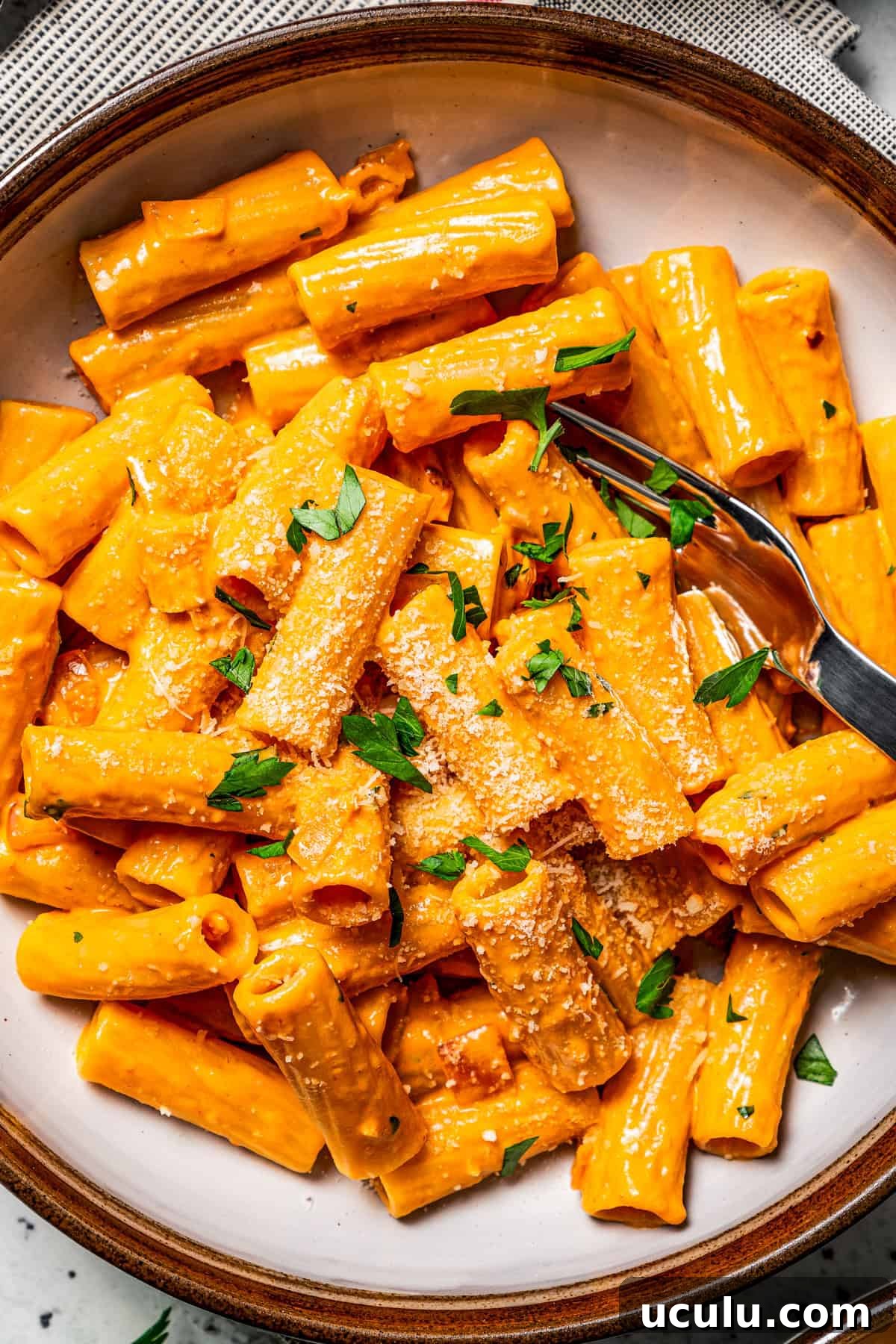 Rigatoni pasta served in a bowl with a fork.