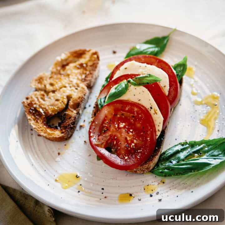 caprese bruschetta served on a plate with an extra slice of toasted bread.