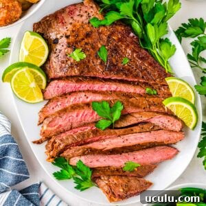 The finished cast iron flank steak sliced and served on a white platter.