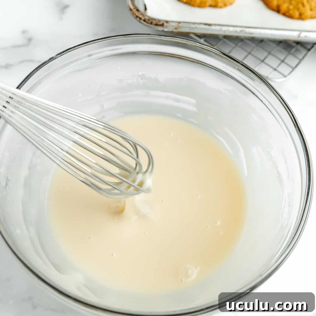 Vanilla Icing in a bowl with a whisk.