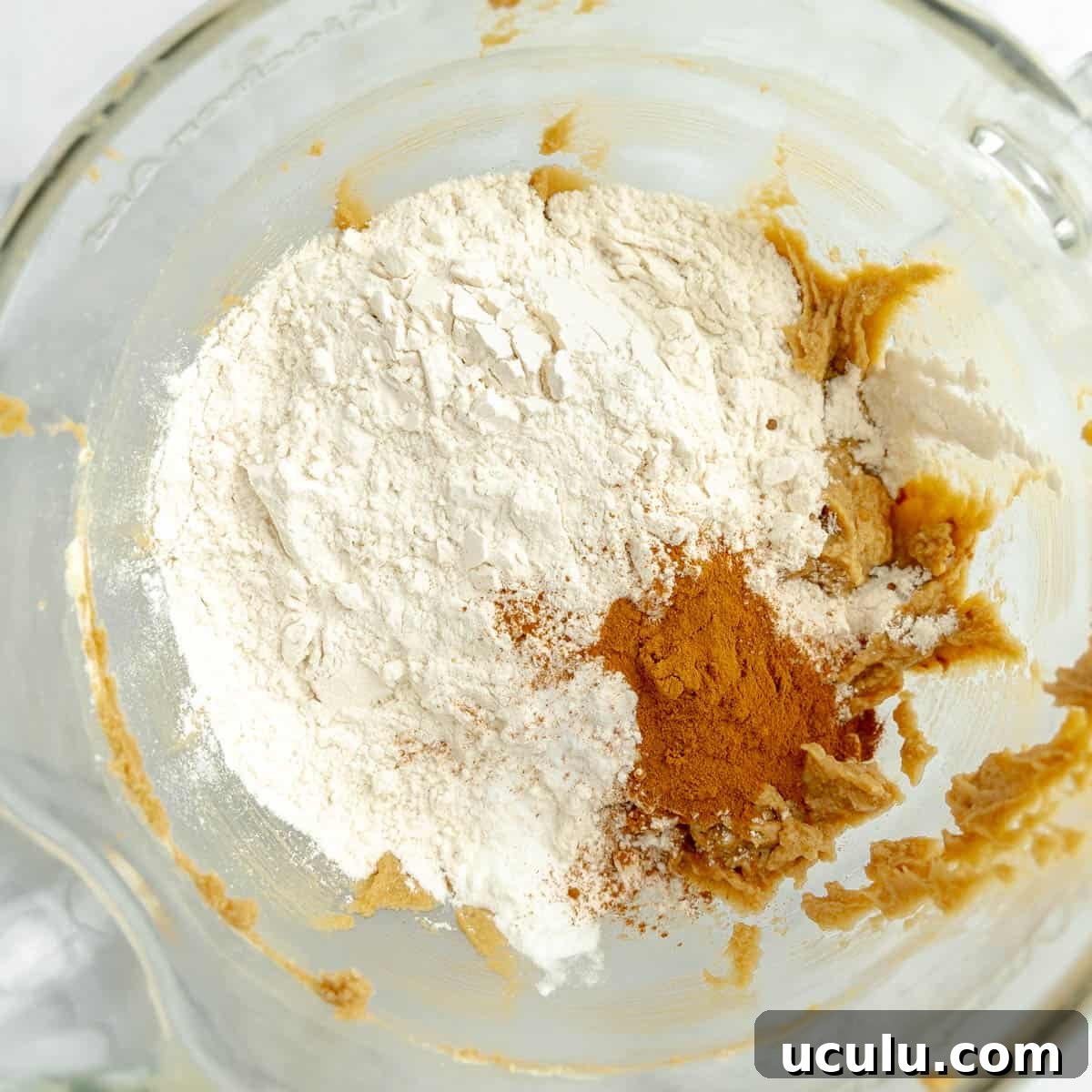 Flour and cinnamon added to a clear mixing bowl.