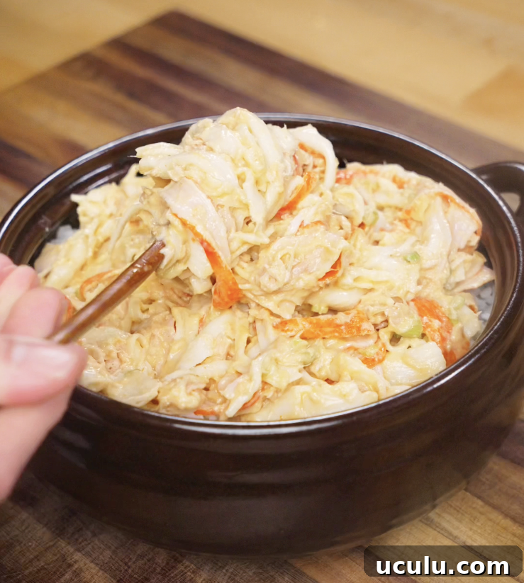 The creamy crab and tuna mixture is spread evenly over a layer of seasoned sushi rice in a dark baking dish.