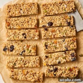 A batch of 12 cut granola bars on a baking paper sheet.