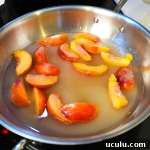 Peaches in water and sugar in a skillet.