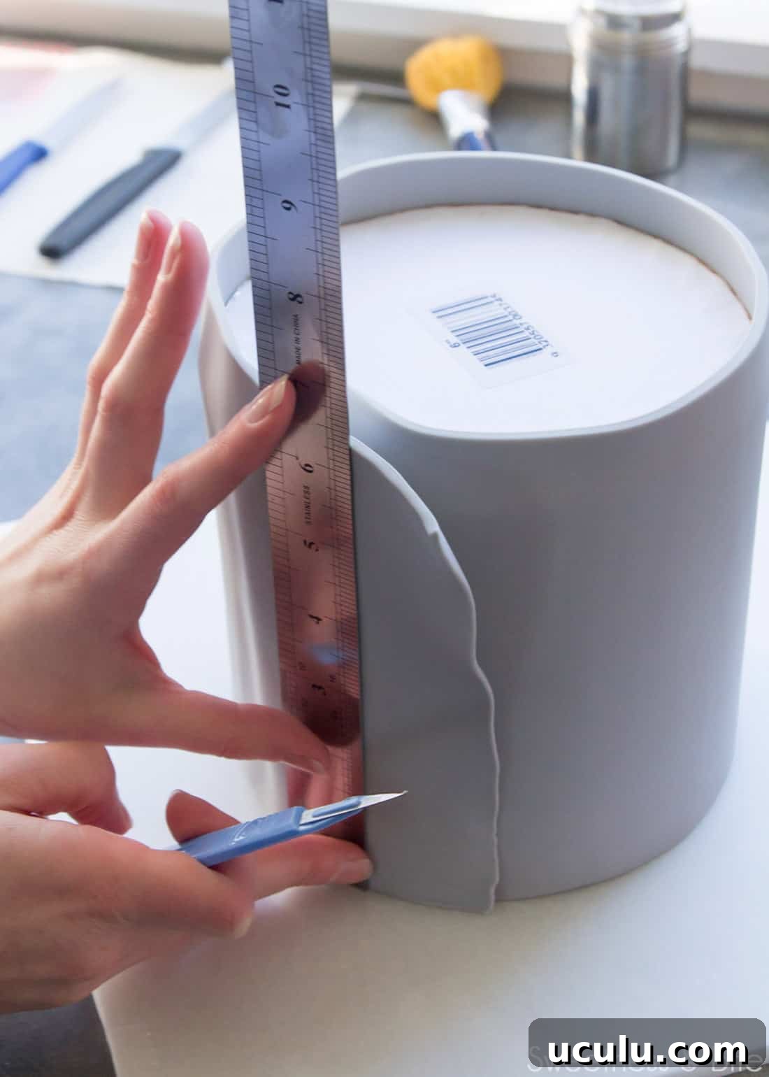 A ruler being held against the cake where the fondant overlaps.