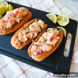 Lobster roll with creamy lobster salad in a toasted bun, garnished with herbs and lemon.