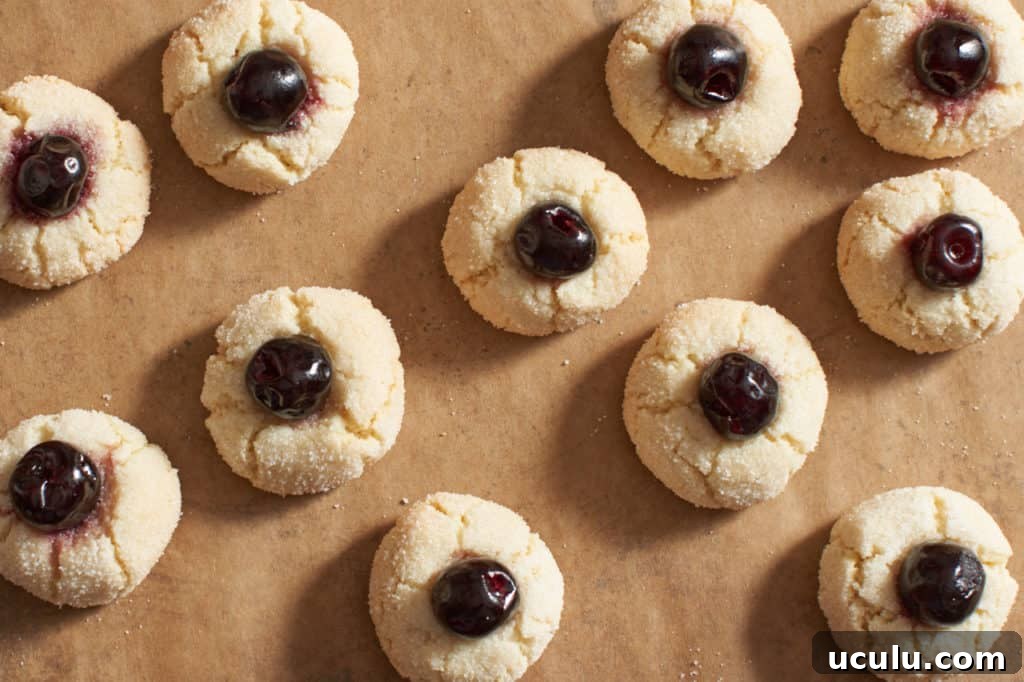 Amaretti cookies with cherries on parchment paper.