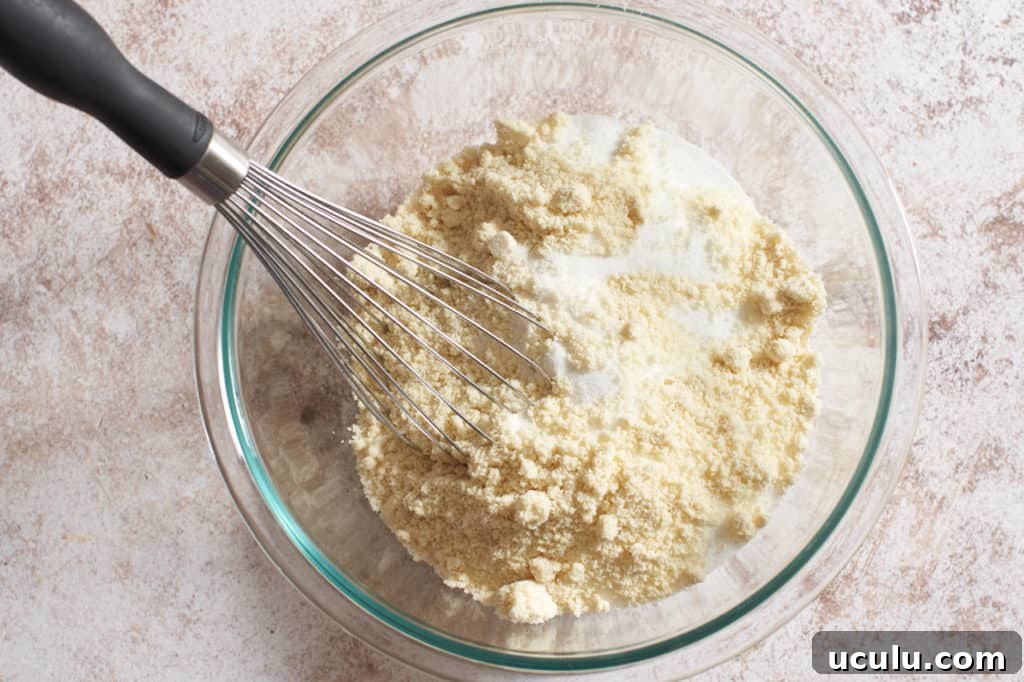 A bowl of dry almond flour and other dry ingredients with a whisk.
